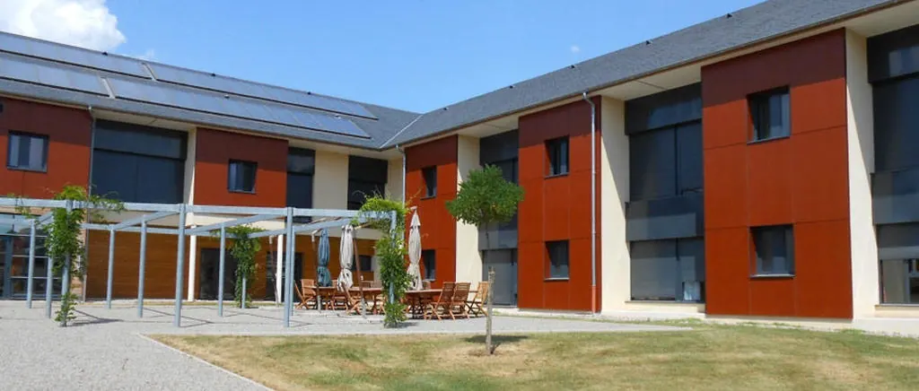 Établissement médico-social récent en R+1, ailes disposées autour d’une cour intérieure avec terrasse et pergola